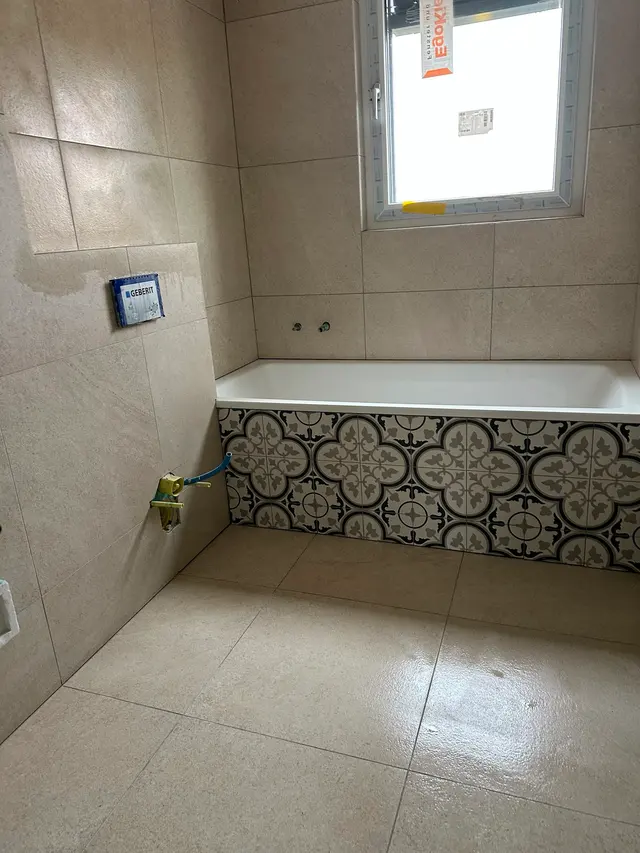 Bad mit Badewanne: Wand und Boden in hellem Grossformat, Wannenverkleidung mit Ornamentplatten