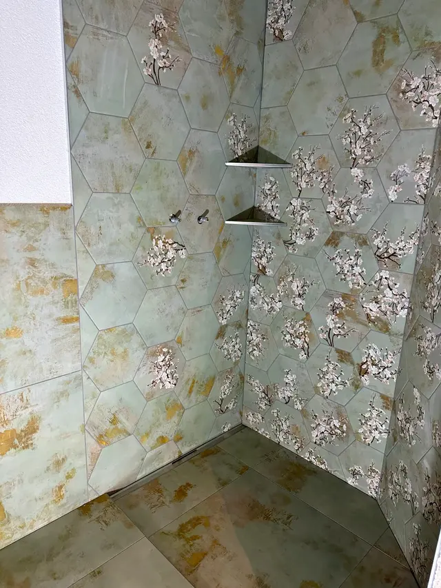 Dusche mit Hexagon-Dekor: Sechseckige Dekorplatten mit Blütenmotiv, Eckablage aus dem gleichen Material