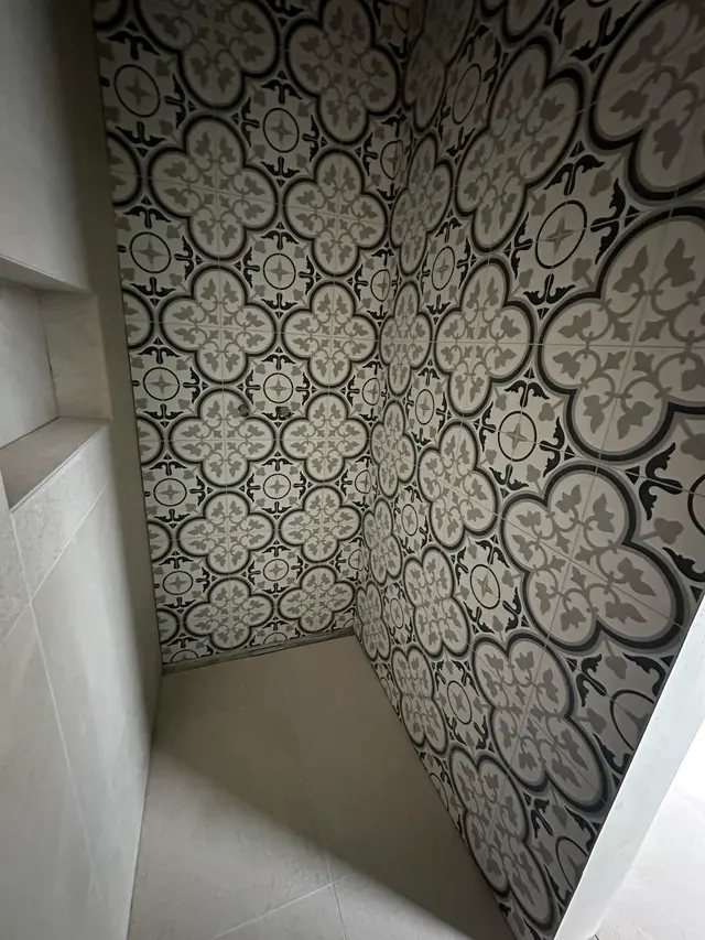 Dusche mit Ornamentplatten: Musterplatten in Schwarz, Weiss und Grau an den Duschwänden, Nische in Platten eingefasst
