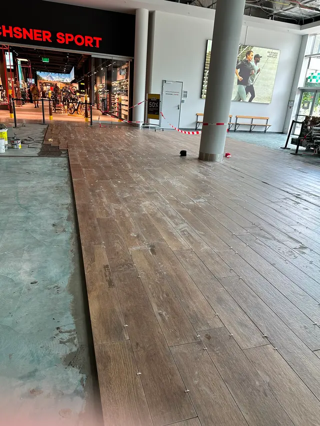 Eingang Ochsner Sport: Holzoptik-Planken im Eingangsbereich, Verlegung im Einkaufszentrum