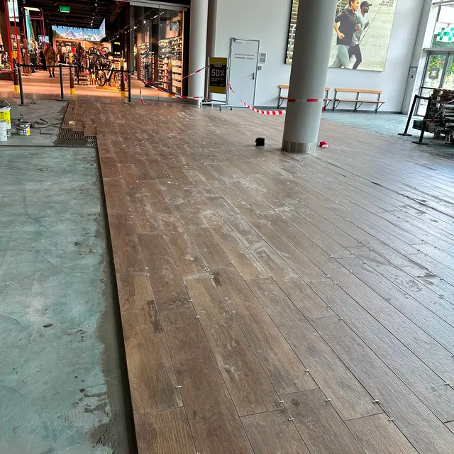 Eingang Ochsner Sport: Holzoptik-Planken im Eingangsbereich, Verlegung im Einkaufszentrum