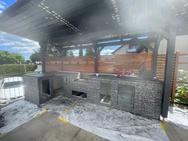 Sitzplatz mit Outdoor-Küche: Grossformatige Terrassenplatten unter der Pergola, rund um die Aussenküche verlegt