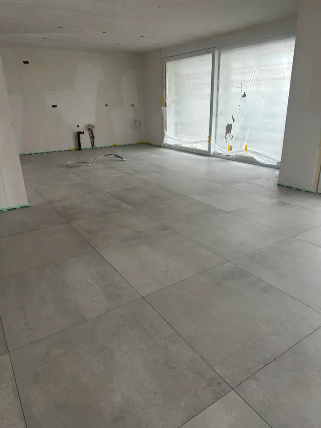 Wohnraum, Neubau: Grossformat in Betonoptik bis zur Fensterfront, Randfuge sauber freigehalten